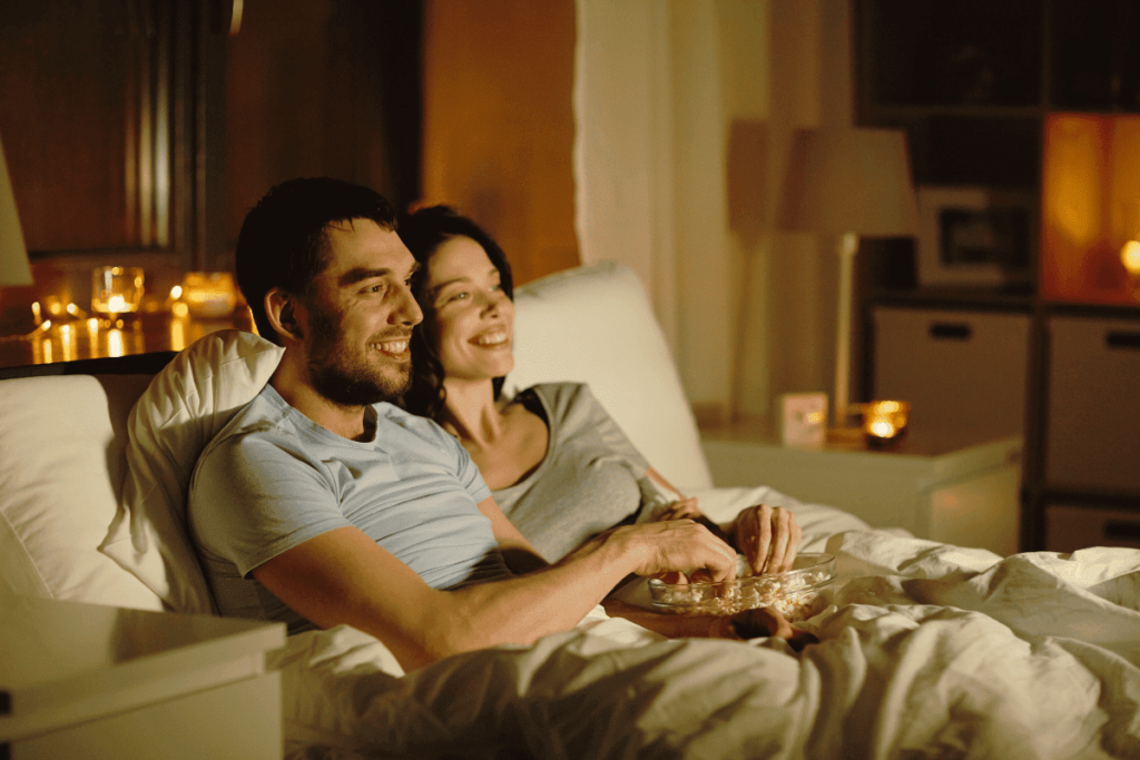 Casal comendo pipoca e assistindo a um filme sentados no sofá.