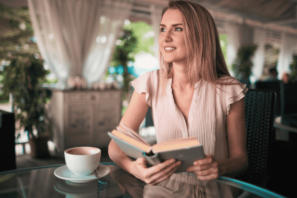 Mulher em um café sozinha lendo um livro.