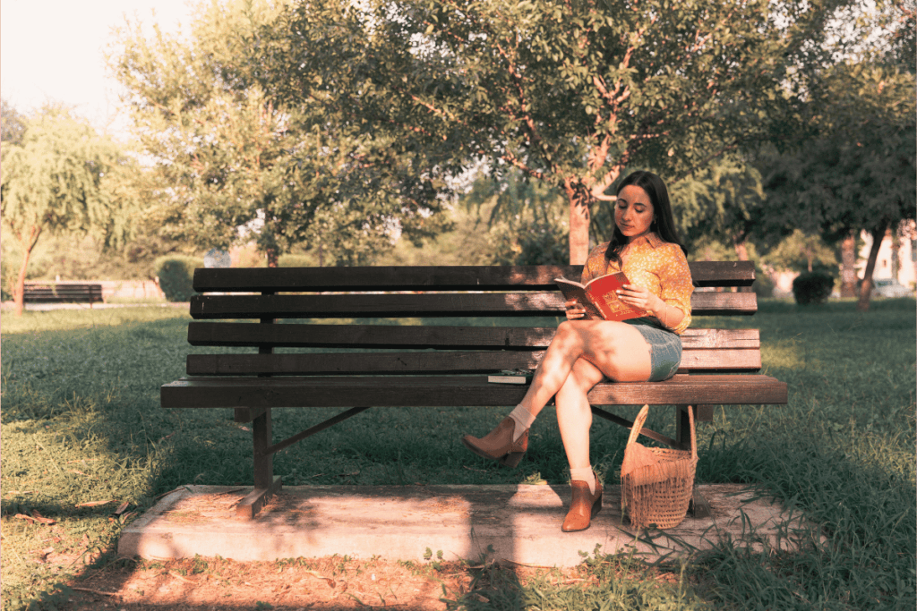 mulher lendo um livro em um banco no parque da cidade